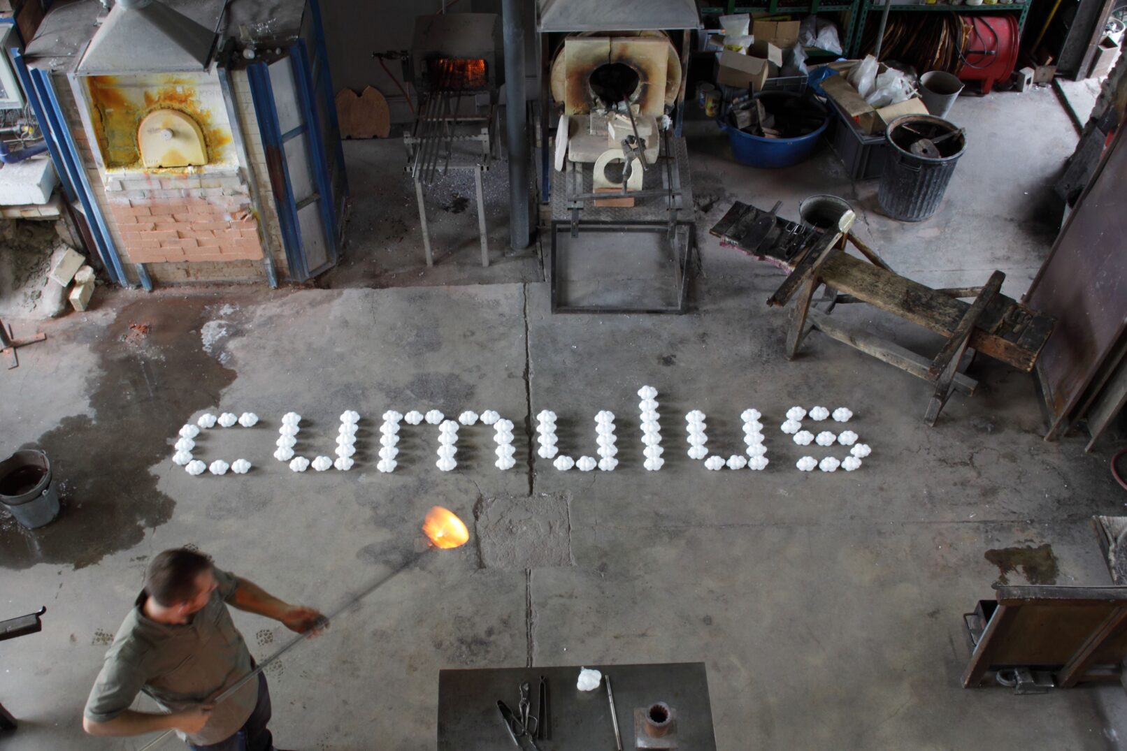 Cumulus glass ornaments displayed as cumulus text on the floor of the glass workshop